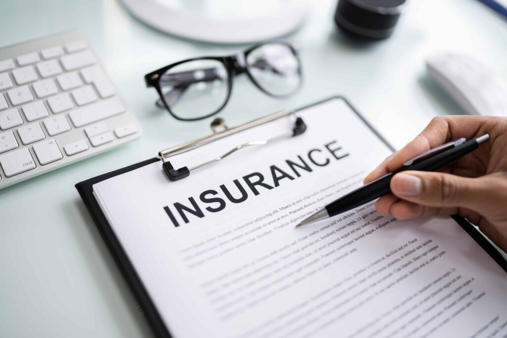 Person reviewing an insurance policy document on clipboard at desk, symbolizing legal and financial protection.